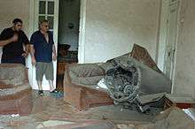 Two men looking at a missile lying across a sofa