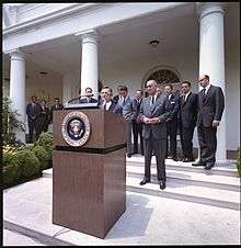 In this photo, David Rockefeller takes the podium as President Lyndon Johnson looks on in the White House Rose Garden on June 15, 1964 to announce the launch of the International Executive Service Corps.