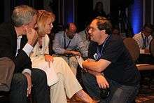 Portrait of Jason Waxman and Diane Bryant (seated) speaking with Charlie Demerjian (kneeling)