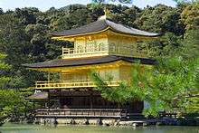 The Golden Pavilion is a building of three storeys with encircling balconies and curving roofs, overlooking a tranquil lake and woods