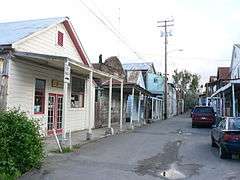 Photograph of a street in Locke, a narrow thoroughfare between tightly packed, single-story, wood-frame buildings.
