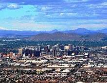 A photo showing the skyline of Phoenix, looking north.  It shows the various buildings of the downtown area, as well as Sunnyslope Mountain in the background