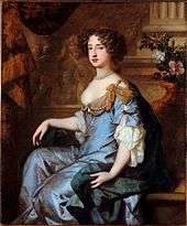 Formal seated portrait of Mary. She wears a grey satin decollatage dress and a blue satin cloak with gold swathes at her shoulders. Her hair is formally arranged in curls and she wears a necklace of large grey pearls.