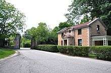 A driveway, gate, and small gatehouse