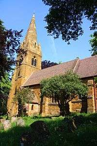 A stone church with a tiled roof; on the left is a tower with a tall spire, and the body of the church extends to the right