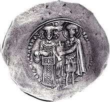 Round silver coin with two standing figures, the left one dressed in regalia and the right one as a warrior saint, handing a castle to the former